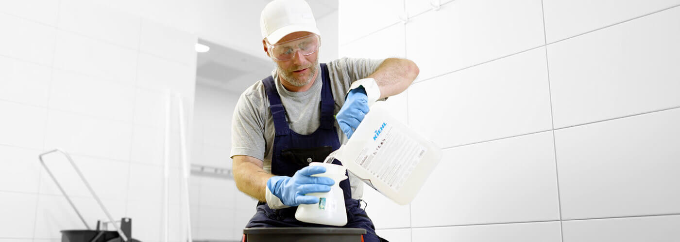 Reinigungsfachkraft erzeugt fachgerecht neue Putzmittelmischung